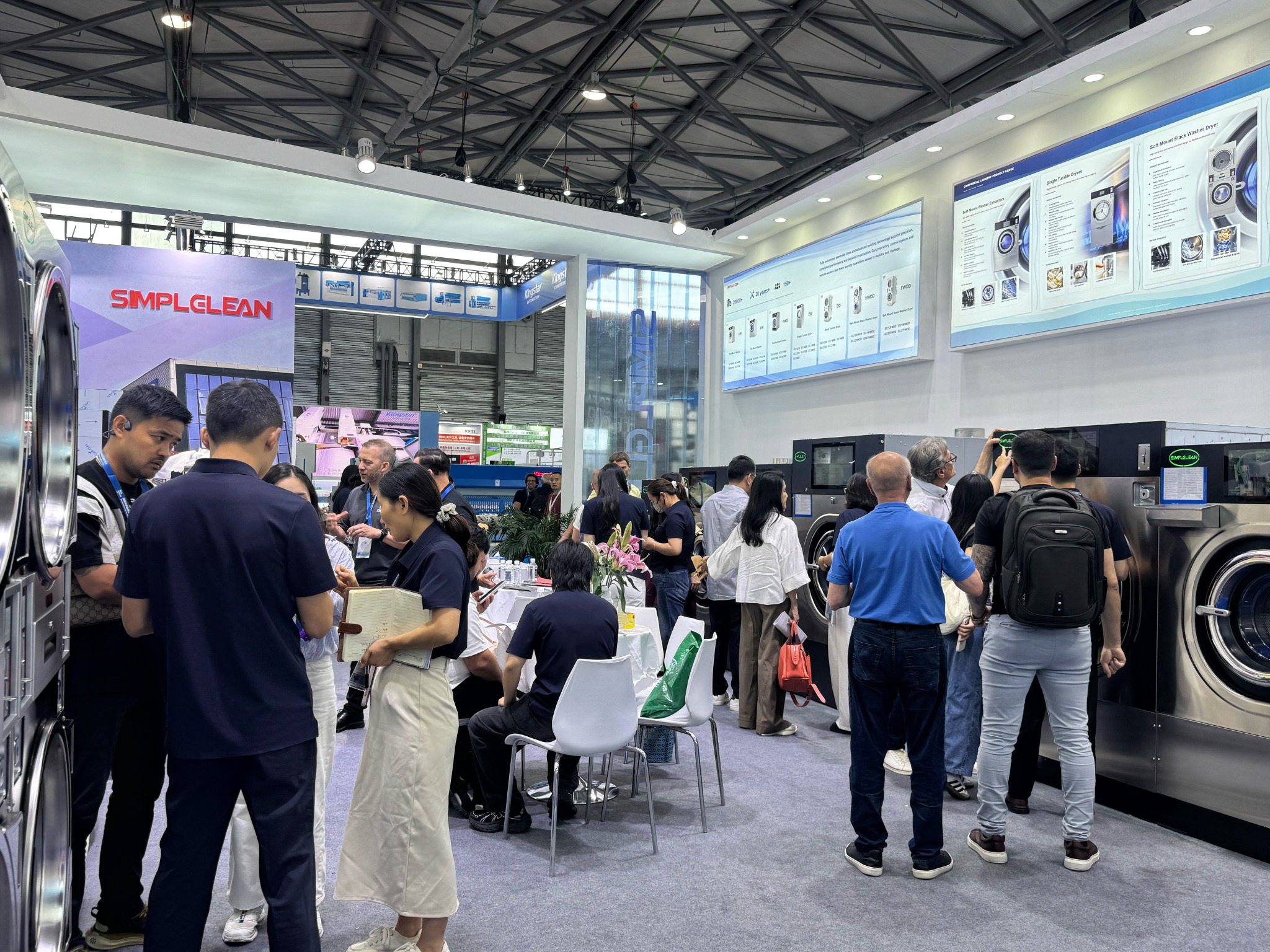 SIMPLECLEAN exhibition booth with commercial laundry equipment and visitors